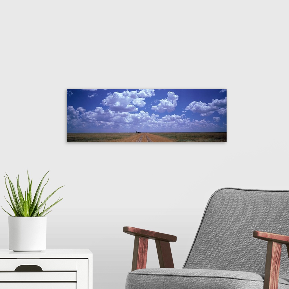 A modern room featuring Panoramic photograph taken at the end of a dirt road with flat fields on both sides and large clo...