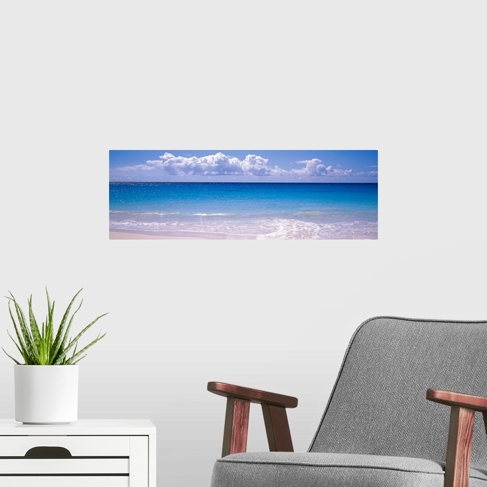 A modern room featuring Panoramic photograph shows the sparkly water of an ocean slowly coming into shore on a bright and...