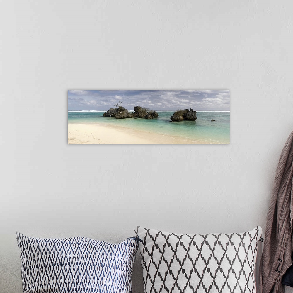 A bohemian room featuring Long horizontal image print of a clear ocean washing ashore past big rocks sticking out of the wa...