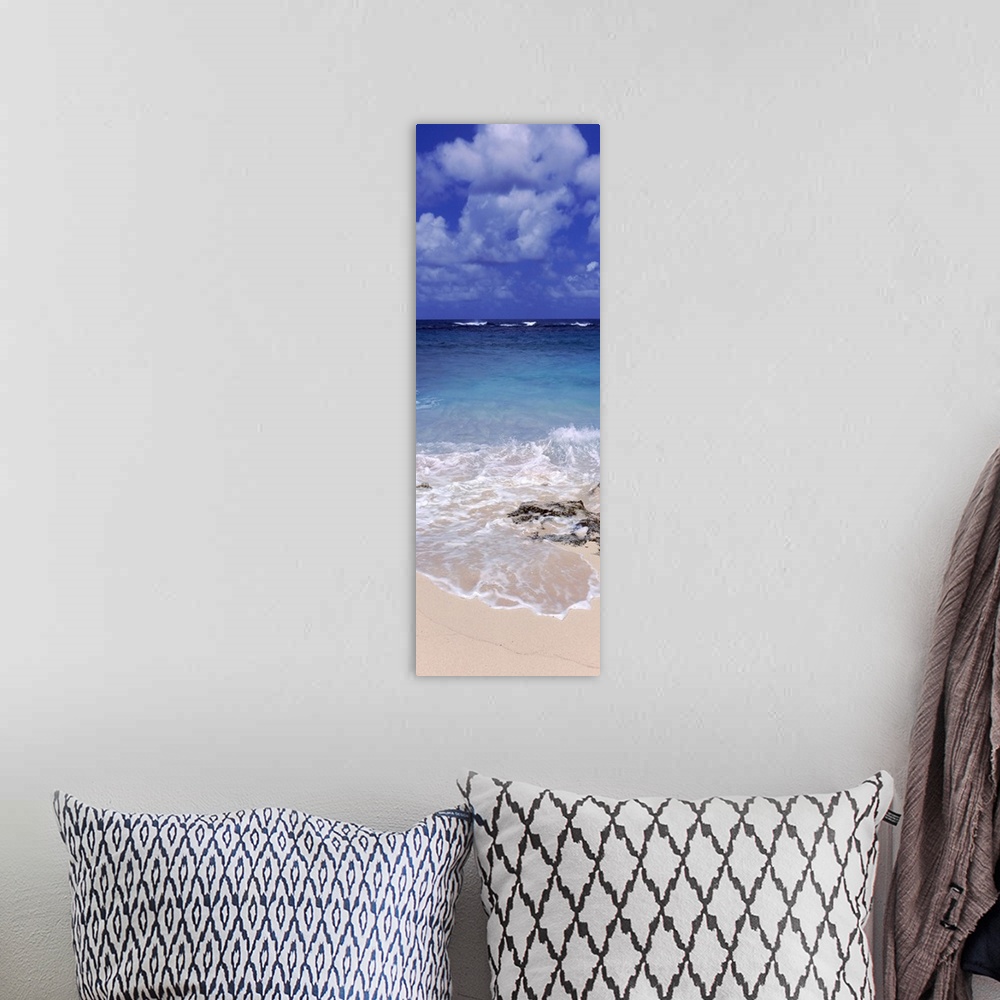 A bohemian room featuring Vertical, large photograph of clear blue waters hitting the beach beneath a blue sky with billowi...