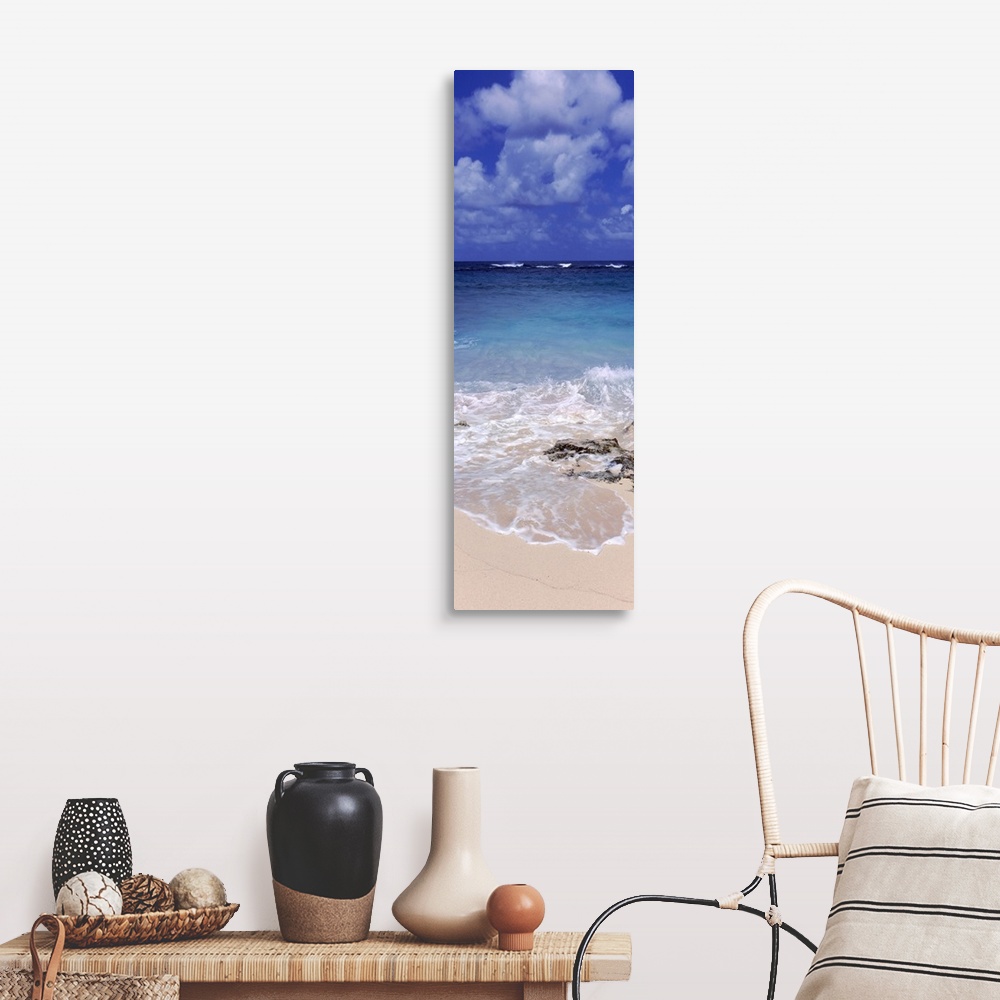 A farmhouse room featuring Vertical, large photograph of clear blue waters hitting the beach beneath a blue sky with billowi...