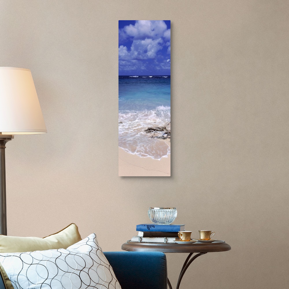 A traditional room featuring Vertical, large photograph of clear blue waters hitting the beach beneath a blue sky with billowi...