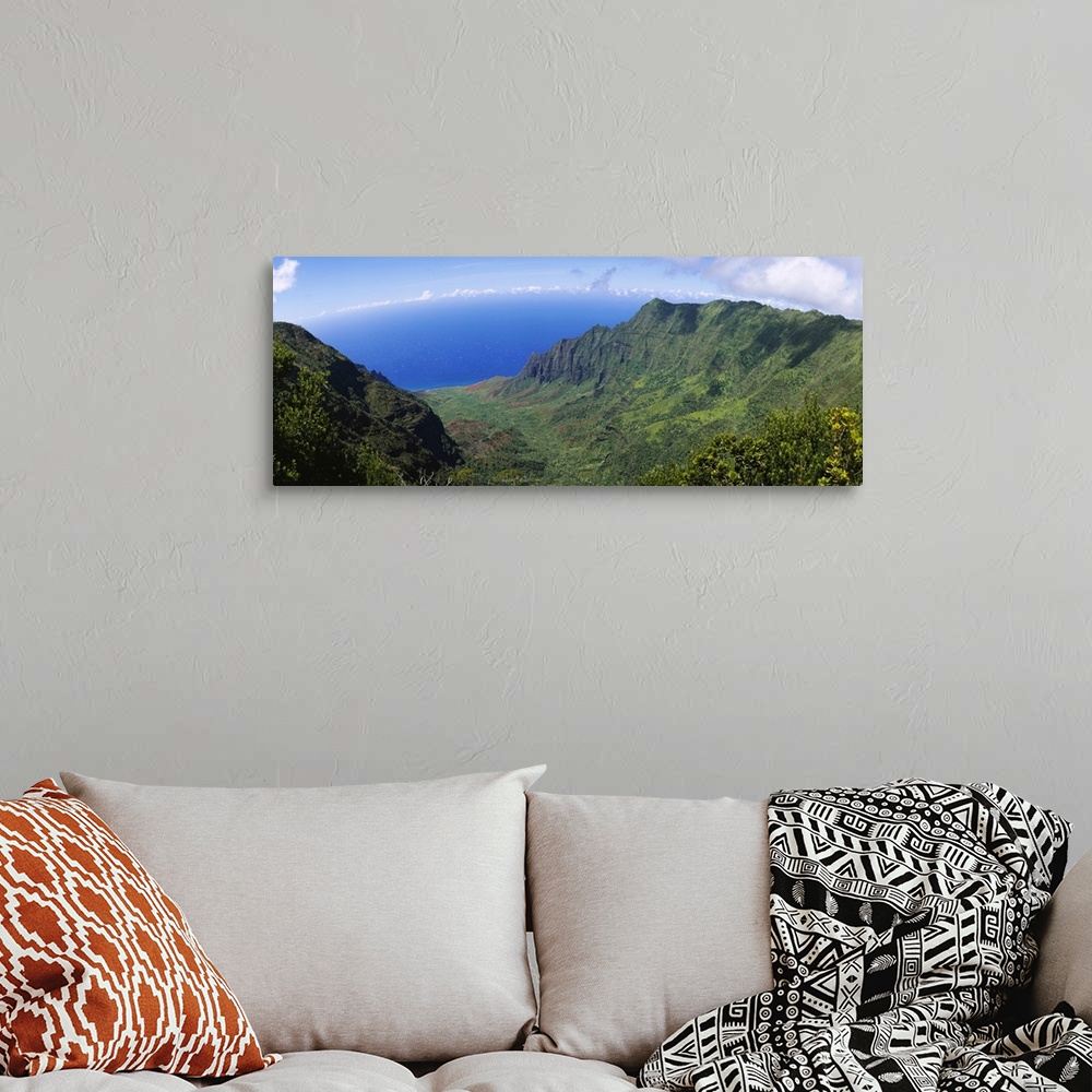 A bohemian room featuring Horizontal photograph on a large wall hanging of a green cliff that overlooks the blue sea, benea...