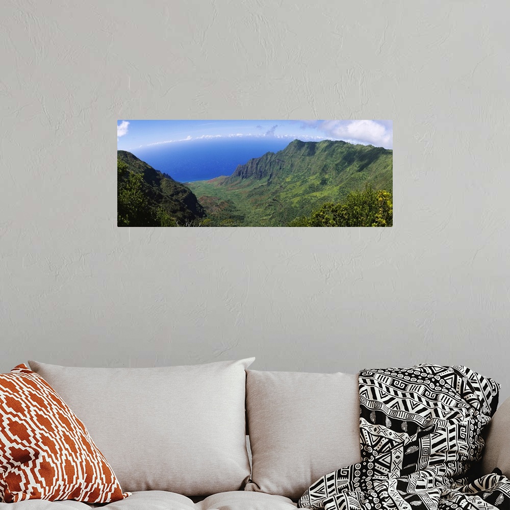 A bohemian room featuring Horizontal photograph on a large wall hanging of a green cliff that overlooks the blue sea, benea...