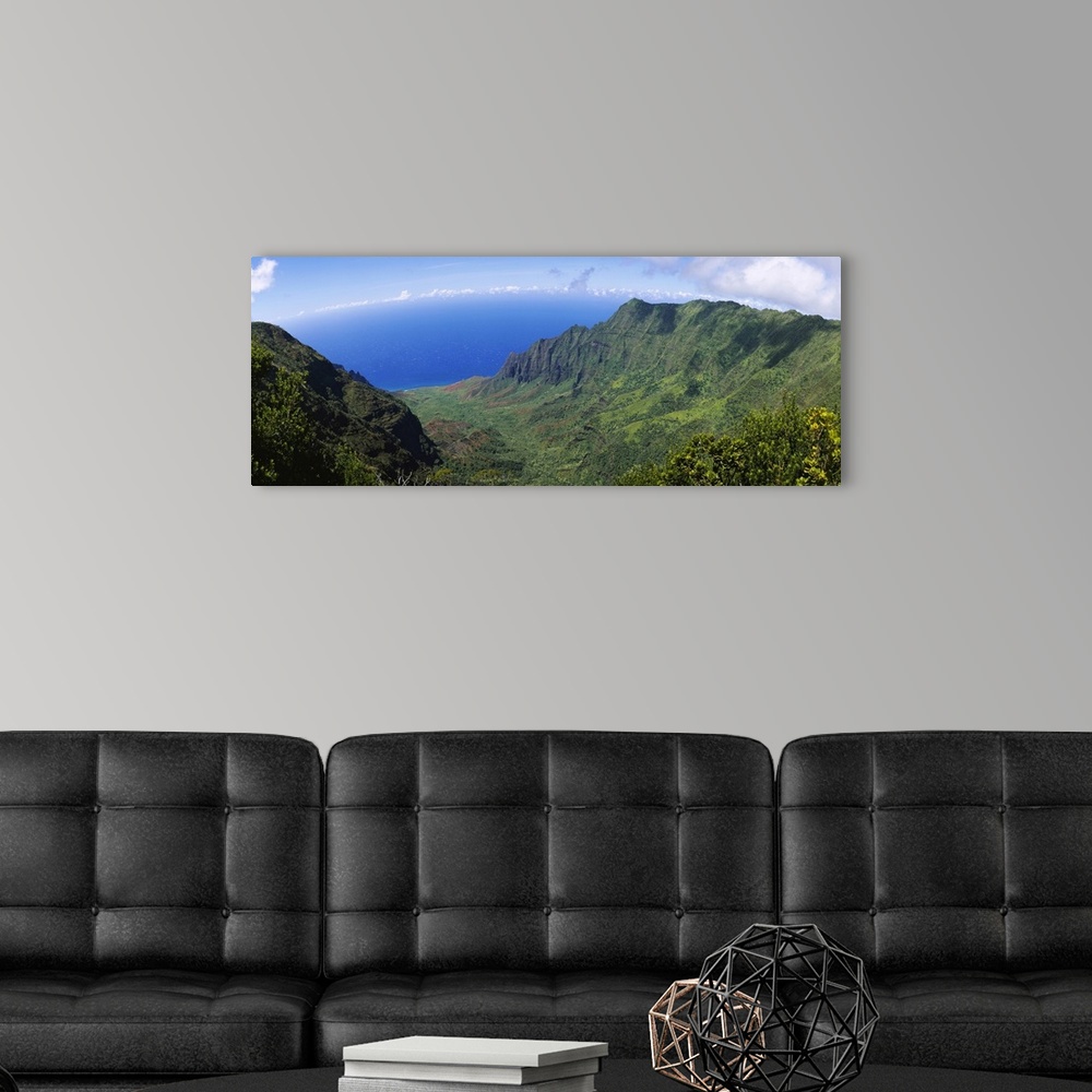 A modern room featuring Horizontal photograph on a large wall hanging of a green cliff that overlooks the blue sea, benea...
