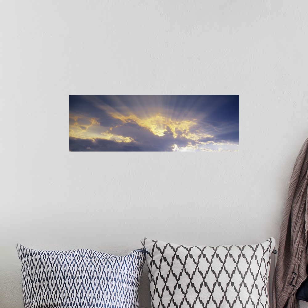 A bohemian room featuring A horizontal canvas photo of sun rays shining through clouds.