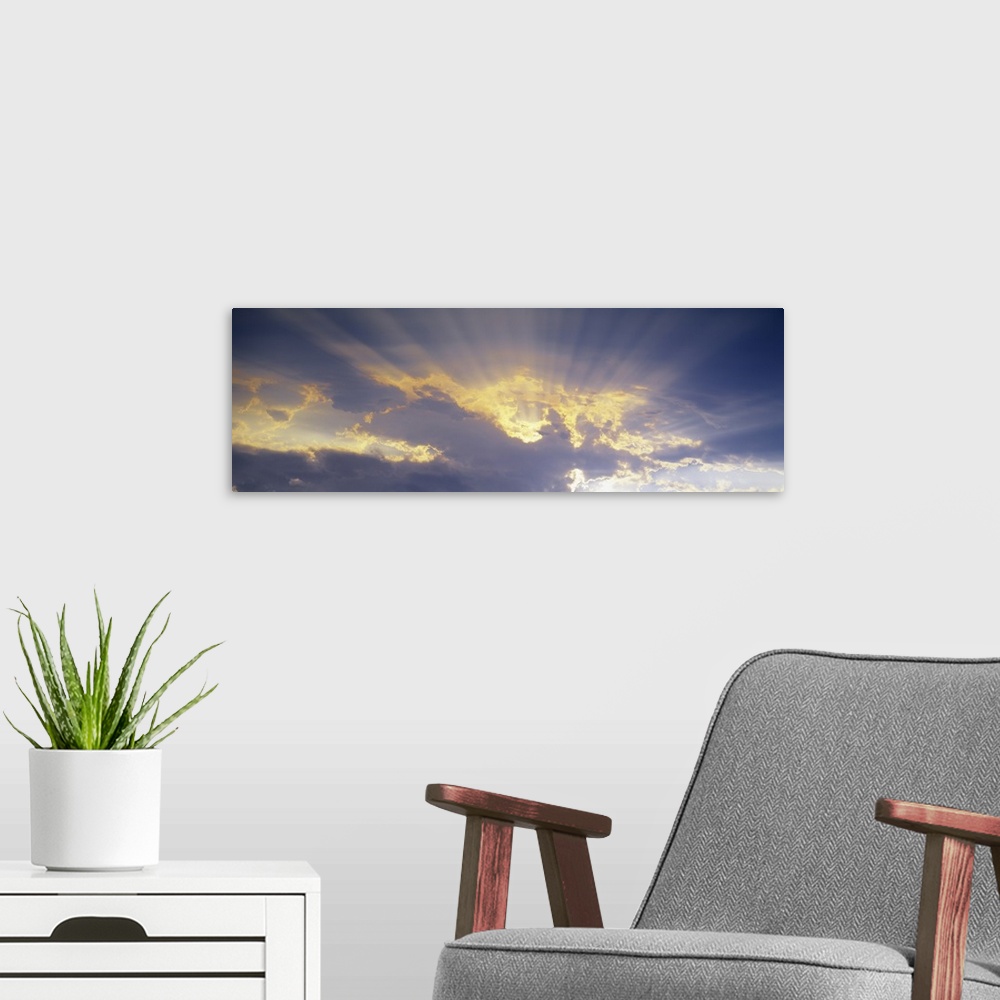 A modern room featuring A horizontal canvas photo of sun rays shining through clouds.