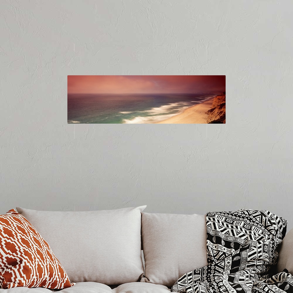 A bohemian room featuring Long photo on canvas of cliffs on the right reaching a beach and crashing ocean waves on the left.