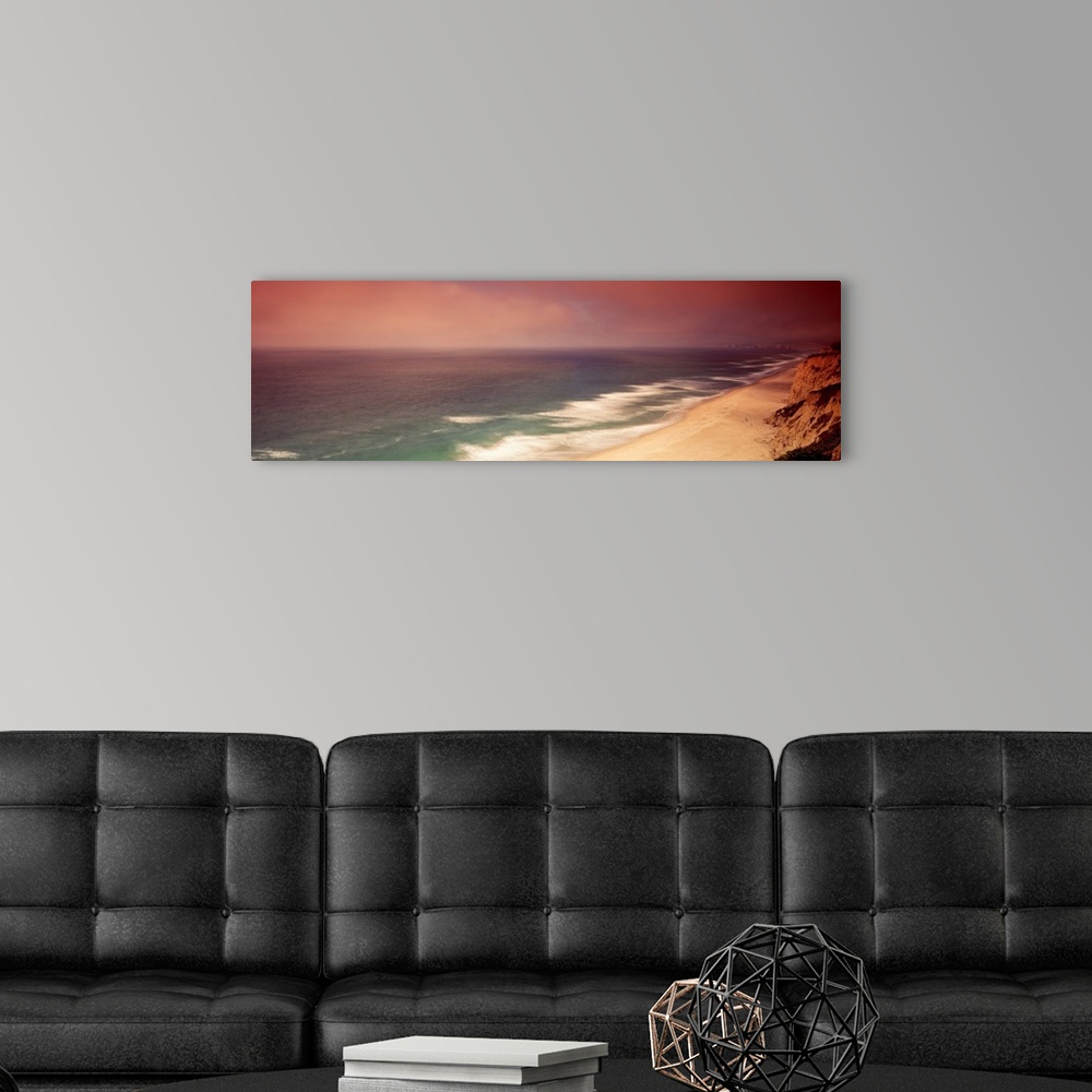 A modern room featuring Long photo on canvas of cliffs on the right reaching a beach and crashing ocean waves on the left.