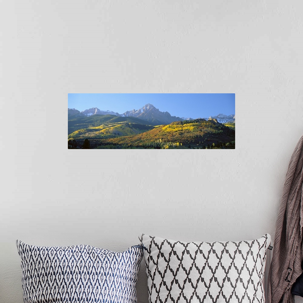 A bohemian room featuring Panoramic photo on canvas of autumn colored trees on rolling hills in front of rugged mountains.
