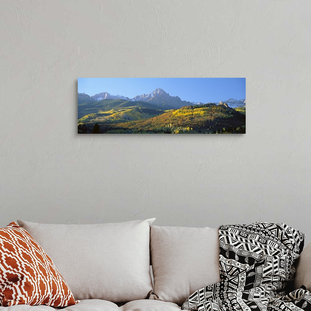 A bohemian room featuring Panoramic photo on canvas of autumn colored trees on rolling hills in front of rugged mountains.