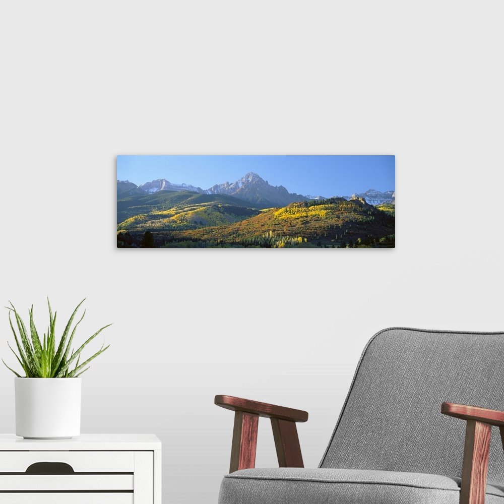 A modern room featuring Panoramic photo on canvas of autumn colored trees on rolling hills in front of rugged mountains.