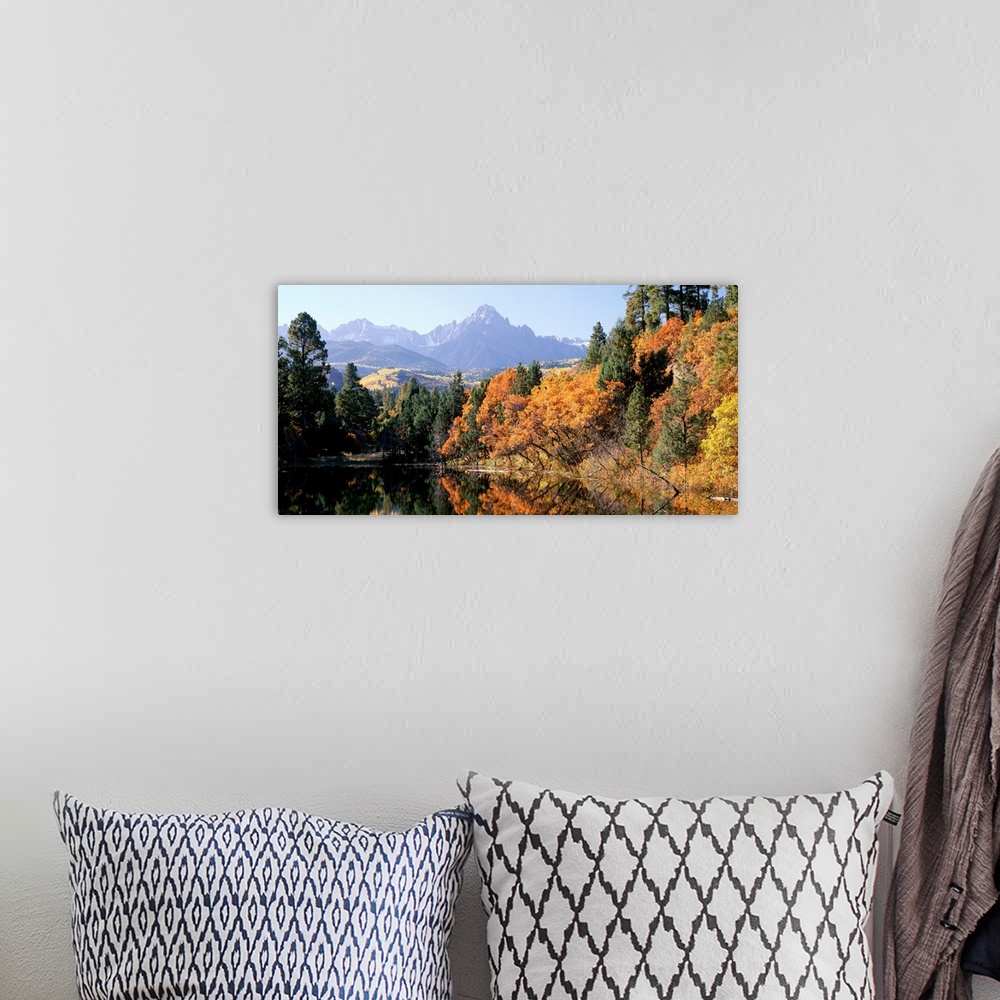 A bohemian room featuring Panoramic photograph displays a colorful forest surrounding a quiet lake in Fall.  In the backgro...