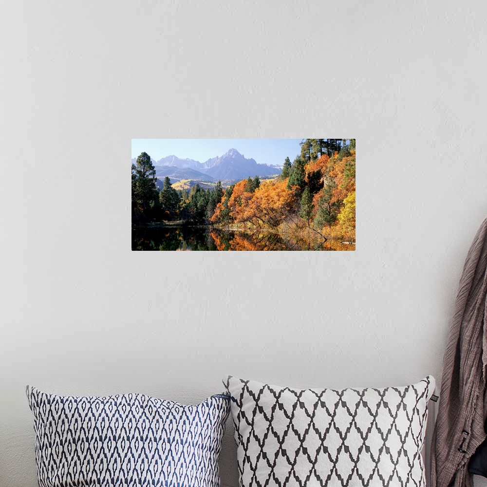 A bohemian room featuring Panoramic photograph displays a colorful forest surrounding a quiet lake in Fall.  In the backgro...