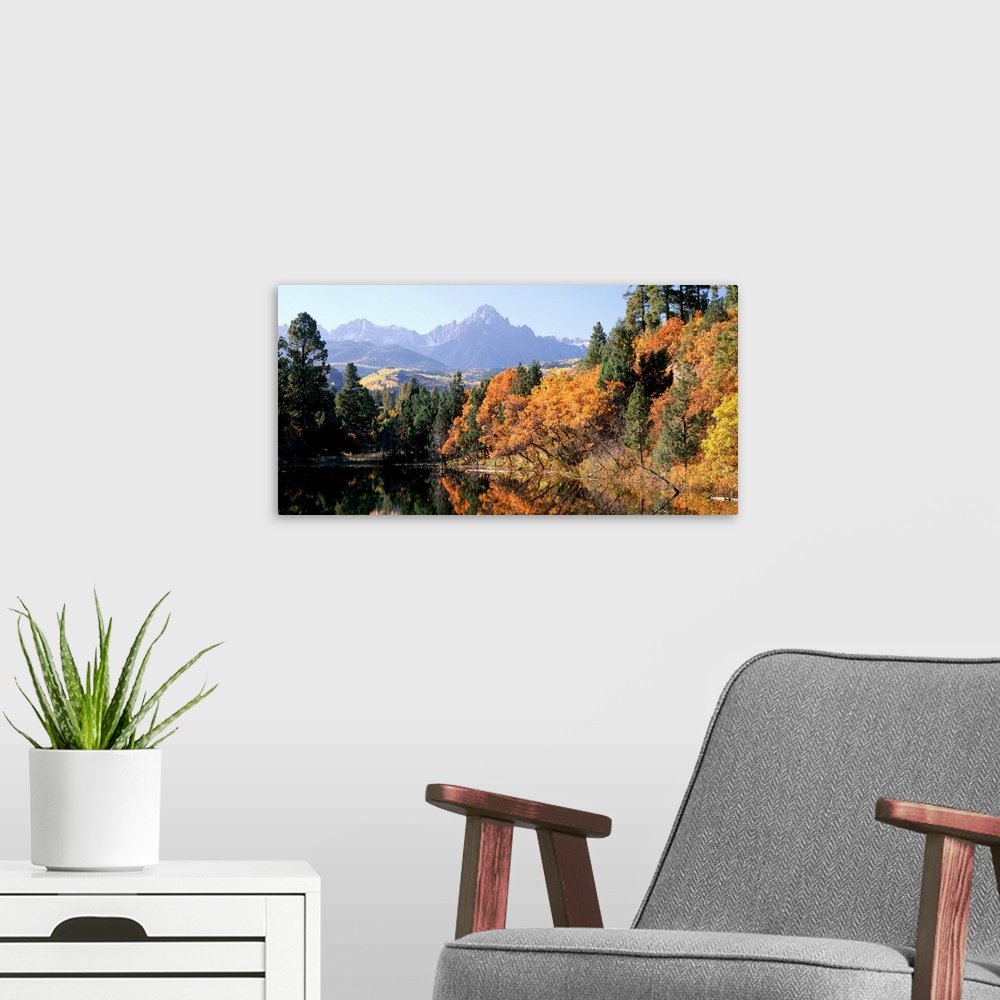 A modern room featuring Panoramic photograph displays a colorful forest surrounding a quiet lake in Fall.  In the backgro...