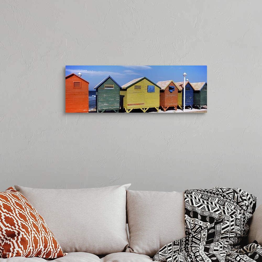 A bohemian room featuring Panoramic photograph taken of multi-colored huts that line the beach with the ocean viewed in the...