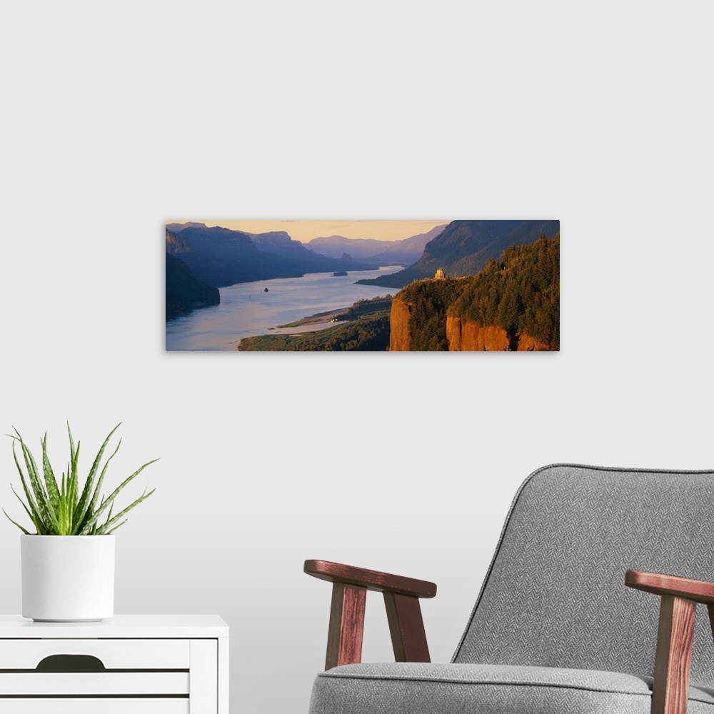 A modern room featuring Panoramic canvas photo of a wide river flowing through rolling mountains and cliffs.
