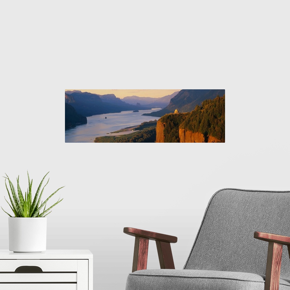 A modern room featuring Panoramic canvas photo of a wide river flowing through rolling mountains and cliffs.