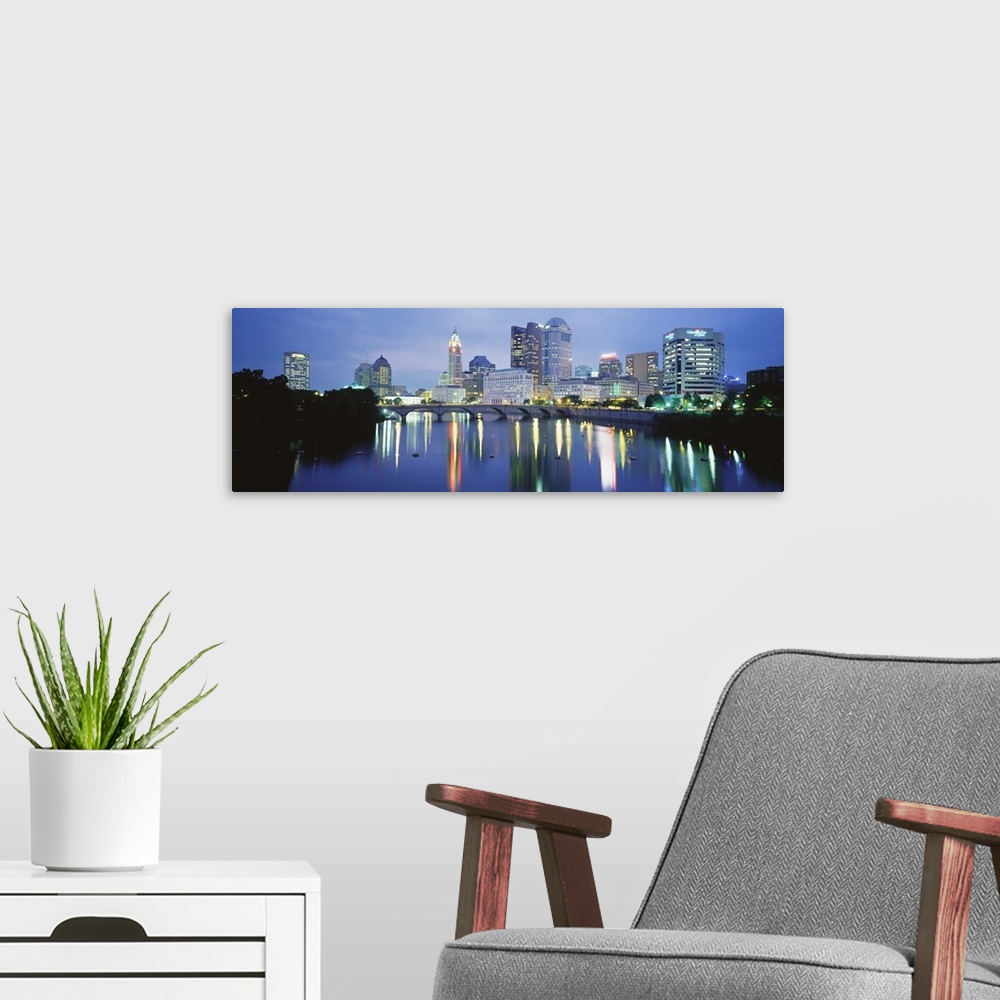 A modern room featuring Giant, horizontal photograph of the Columbus skyline at night, reflecting in the waters of the Sc...