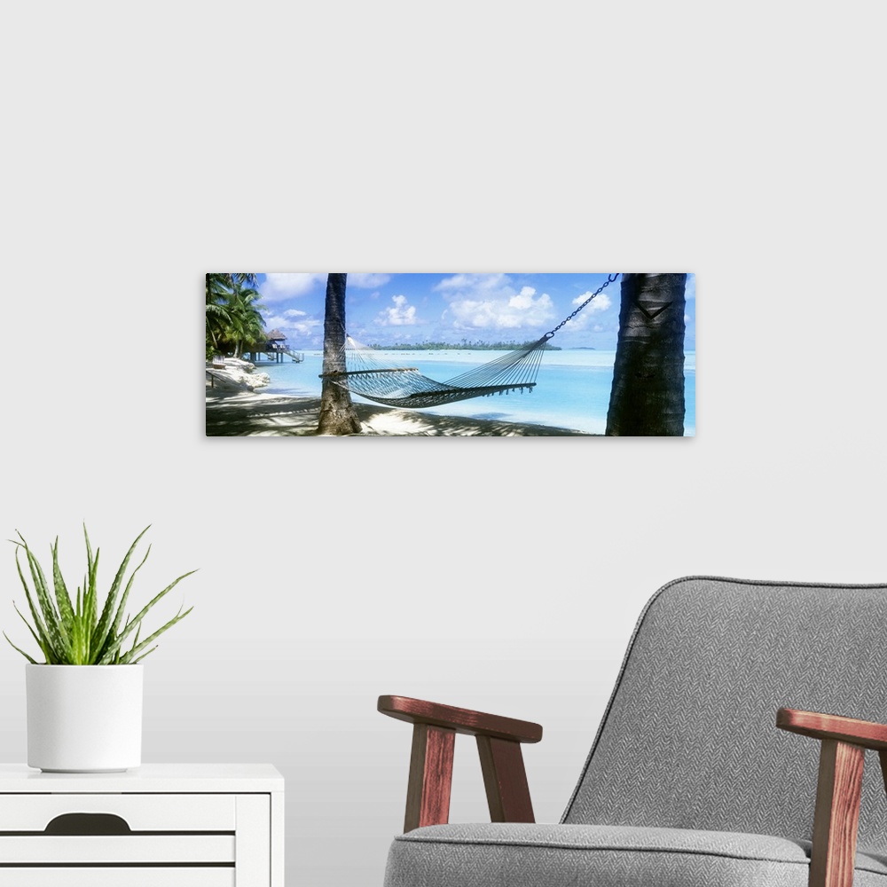 A modern room featuring Panoramic photograph of a hammock hanging between two palm along the shore of the Cook Islands, c...