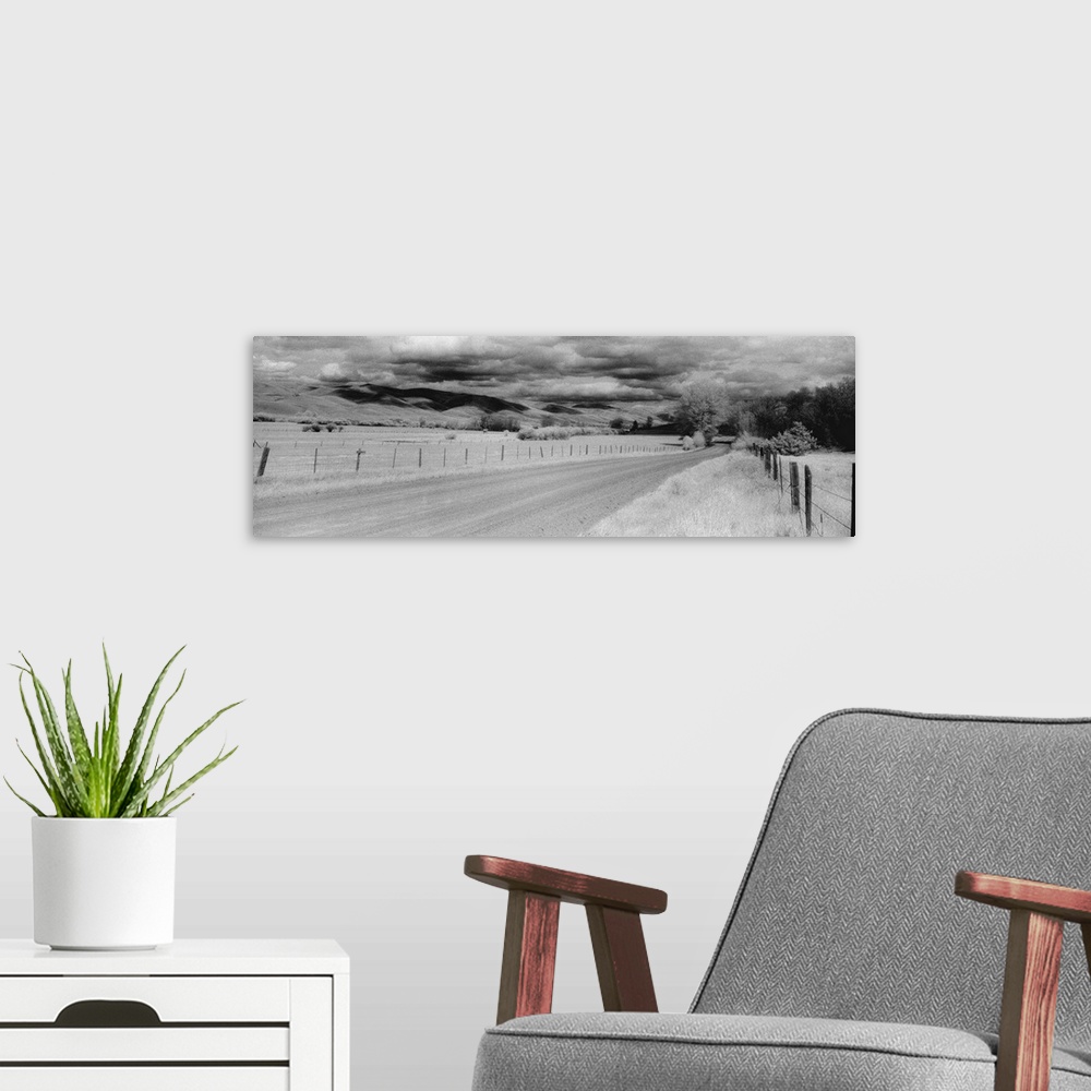 A modern room featuring This black and white panoramic photograph is of a long dirt road that is lined on either side by ...