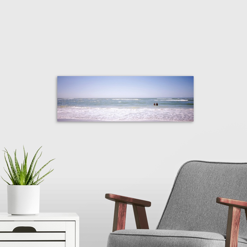 A modern room featuring Panoramic image on canvas of the ocean with two people standing in it.