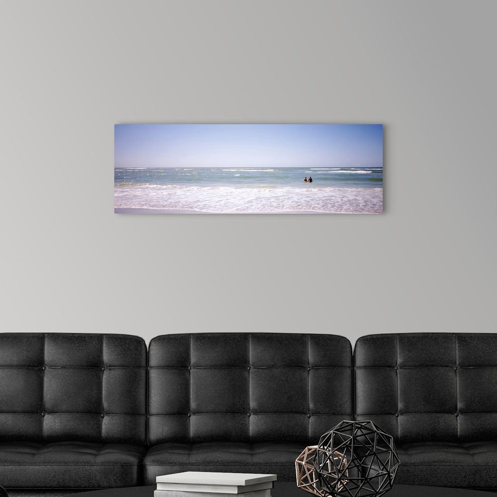 A modern room featuring Panoramic image on canvas of the ocean with two people standing in it.