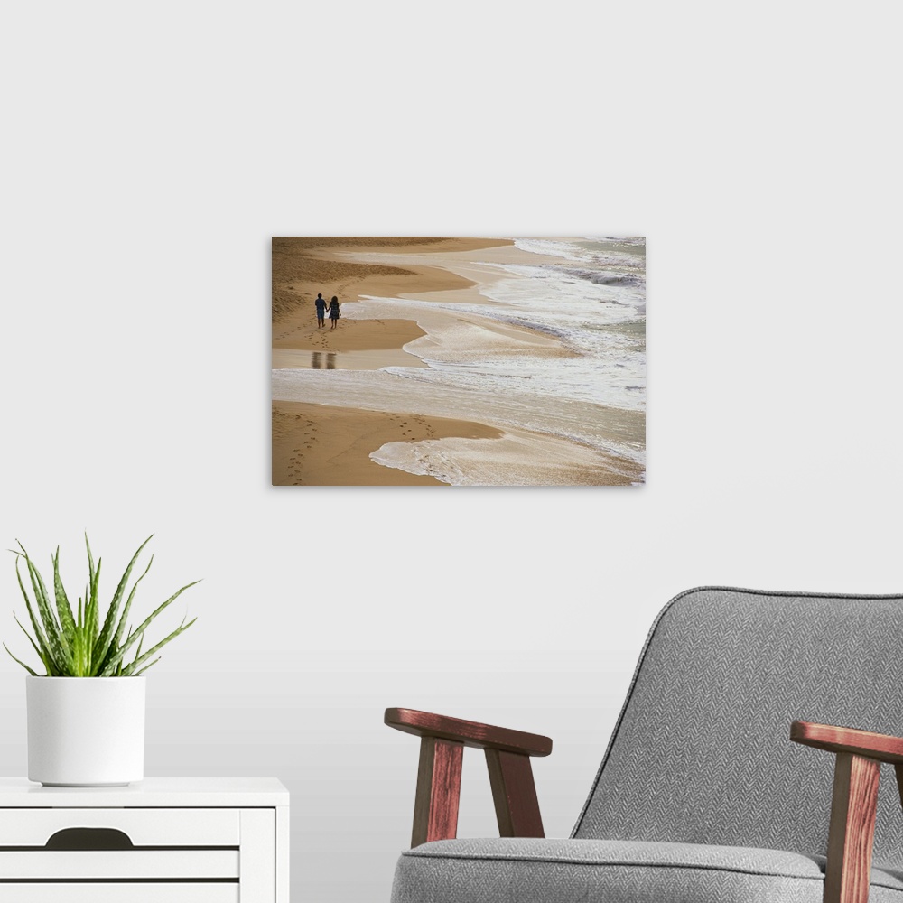 A modern room featuring Giant photograph displays two people holding hands and strolling down a sandy shoreline while the...