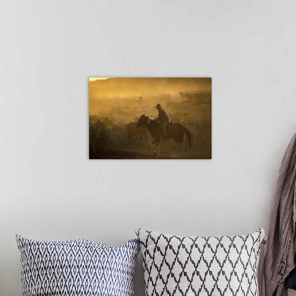 A bohemian room featuring A cowboy on his horse moves cattle during sun down.