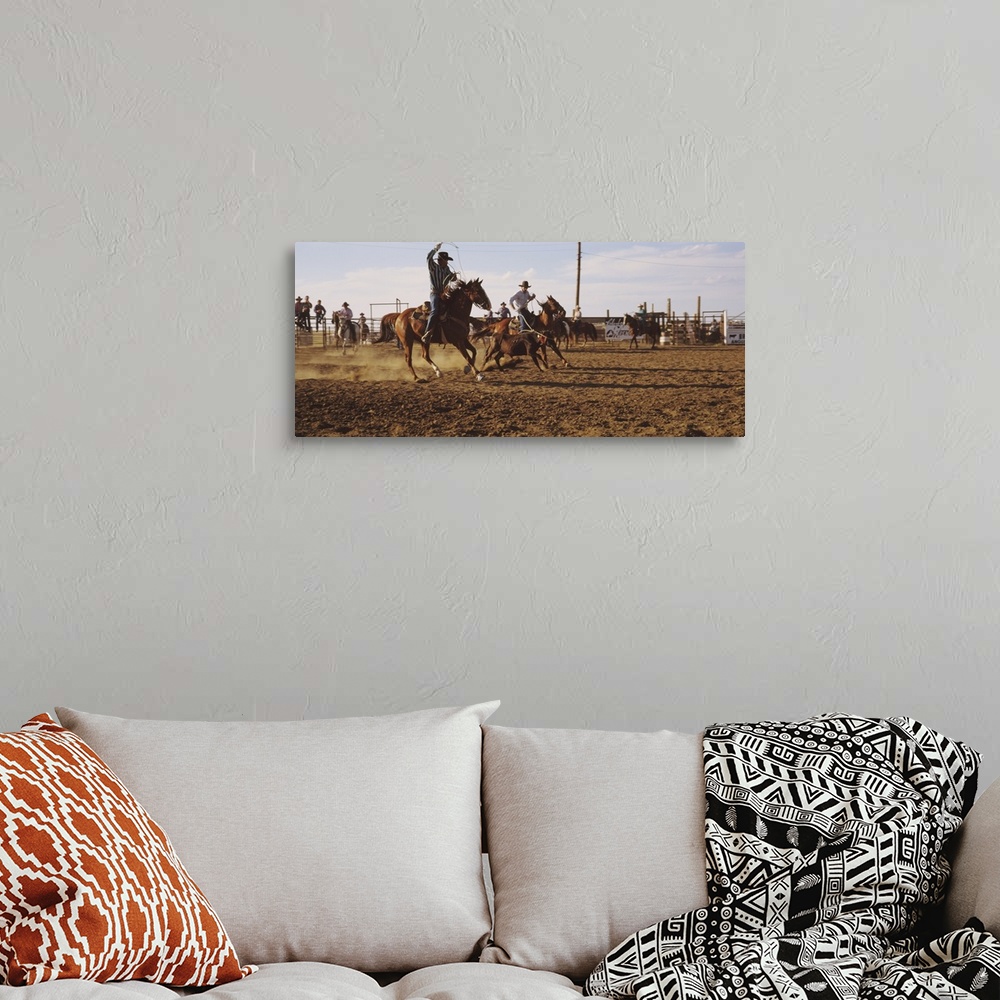 A bohemian room featuring Panoramic photo on canvas of men riding horses trying to rope a baby cow.