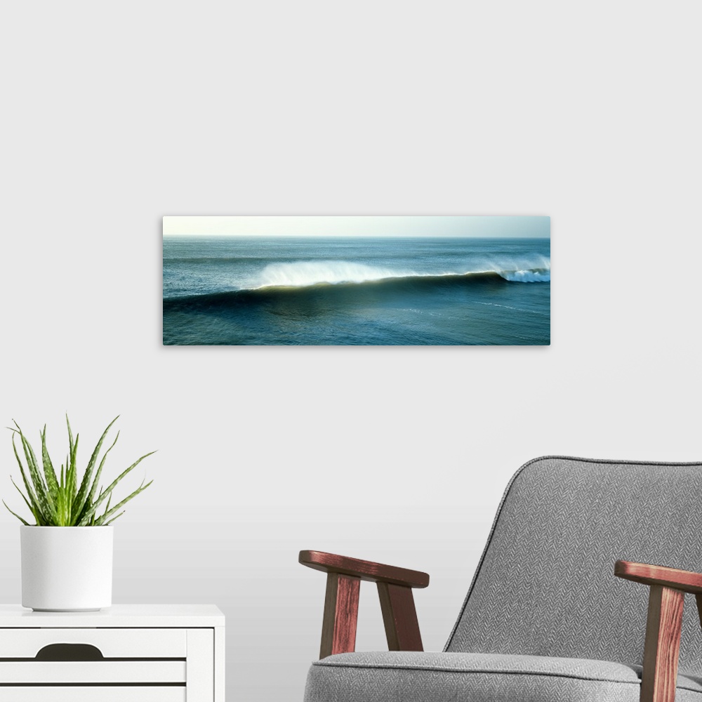 A modern room featuring Wide angle view of an immense wave during sunrise that has begun to curl on the far right of the ...
