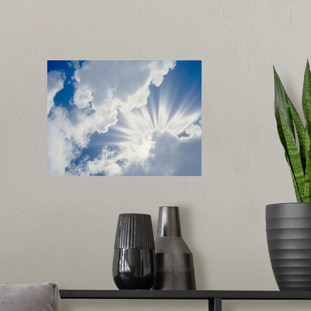 A modern room featuring Large photograph of the sky on a cloudy day with the sun's rays about to break through.