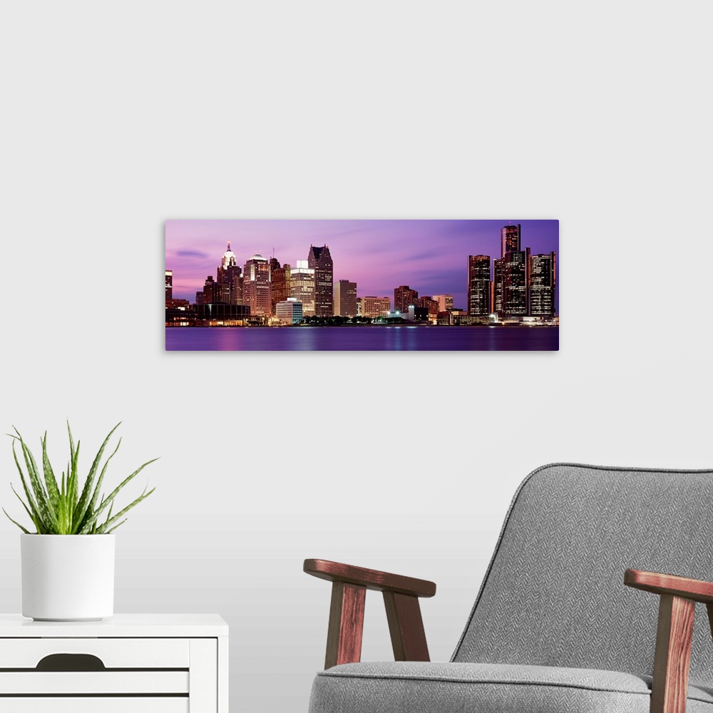 A modern room featuring A panoramic photographic taken on a calm evening, this wall art shows the cityscape lit up at nig...