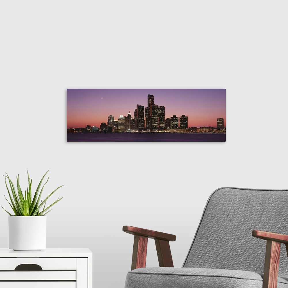 A modern room featuring Panoramic photograph of skyline and waterfront lit up at sunset with the moon high in the sky.