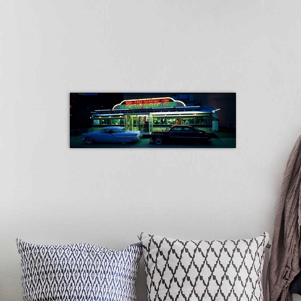 A bohemian room featuring Panoramic photograph of two vintage cars sitting outside of a lit up eatery at night with neon si...