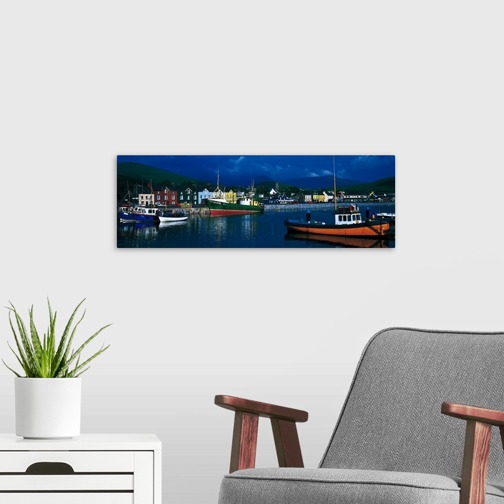 A modern room featuring Panoramic photograph of colorful variety of boats in the water, in front of a row of multi-colore...