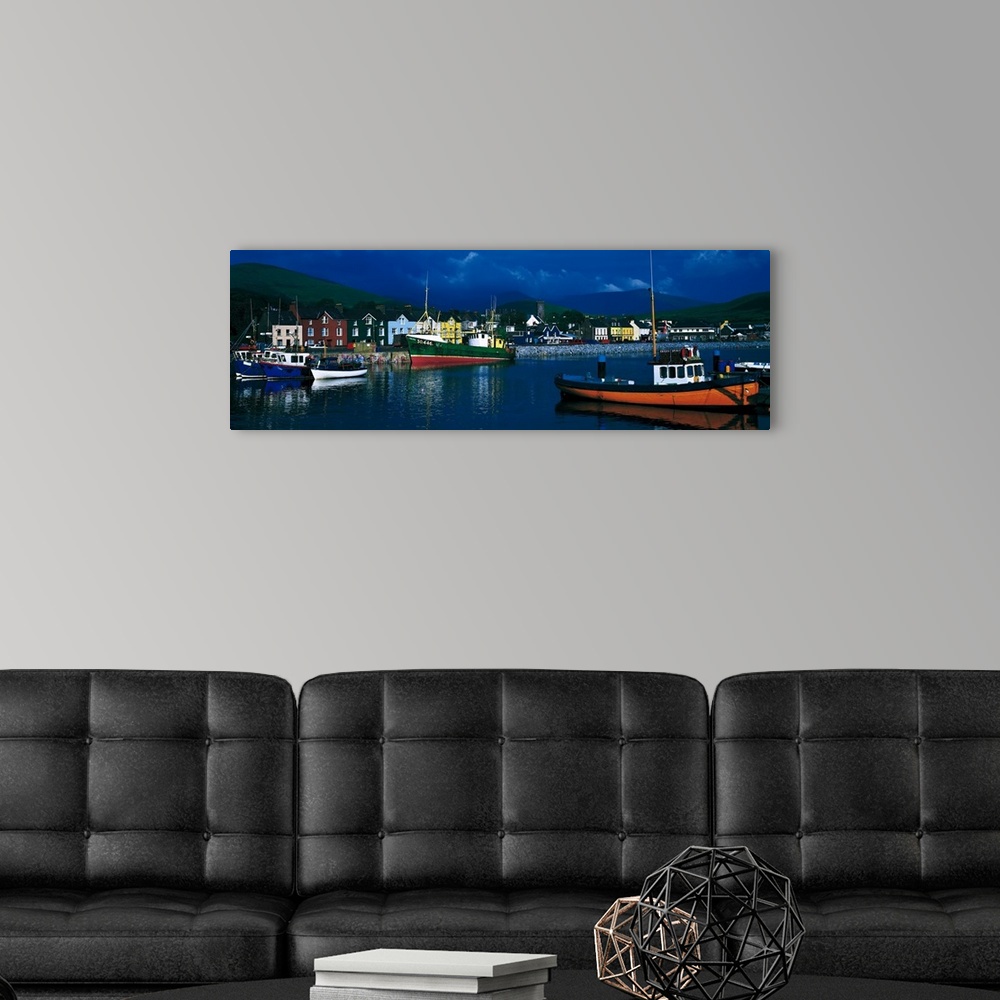 A modern room featuring Panoramic photograph of colorful variety of boats in the water, in front of a row of multi-colore...