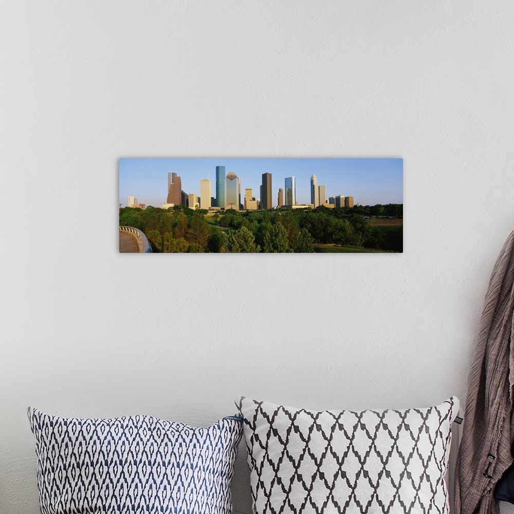 A bohemian room featuring Skyscrapers in the Houston skyline are photographed from a distance with large trees in the foreg...