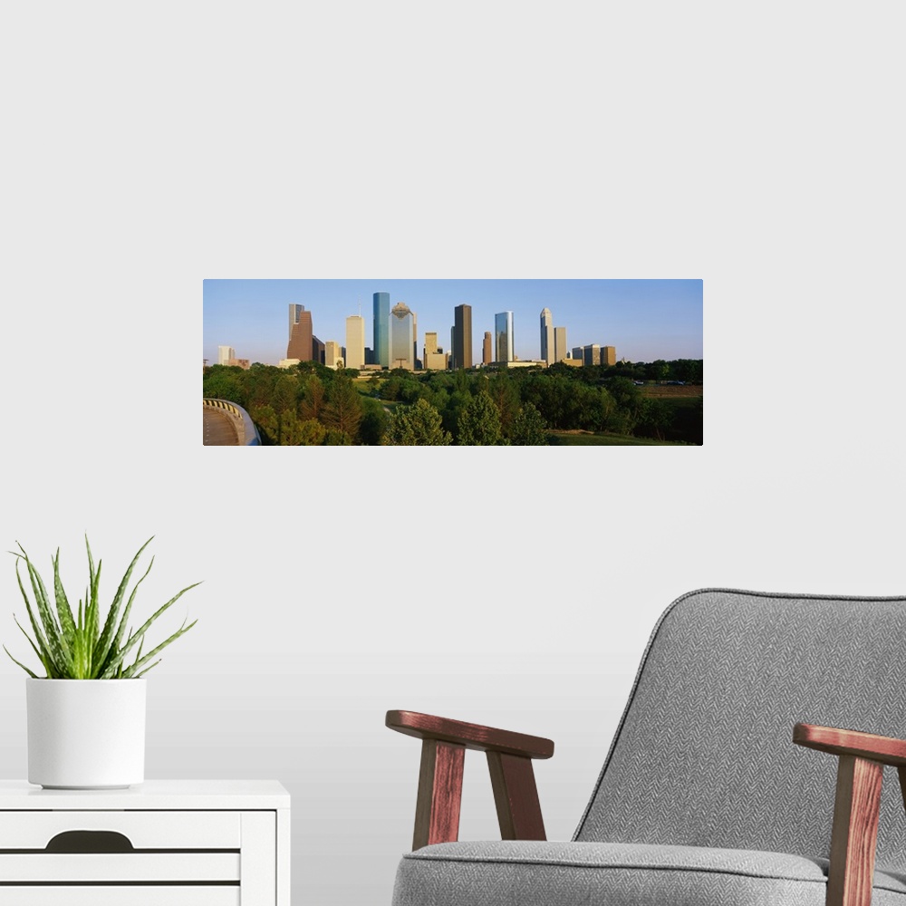 A modern room featuring Skyscrapers in the Houston skyline are photographed from a distance with large trees in the foreg...