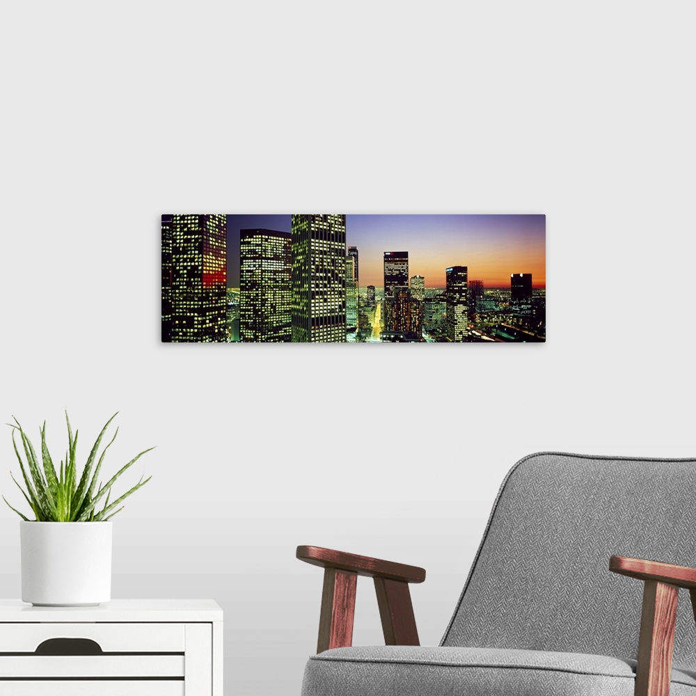 A modern room featuring Panoramic photo of an illuminated cityscape up close to the buildings at sunset.