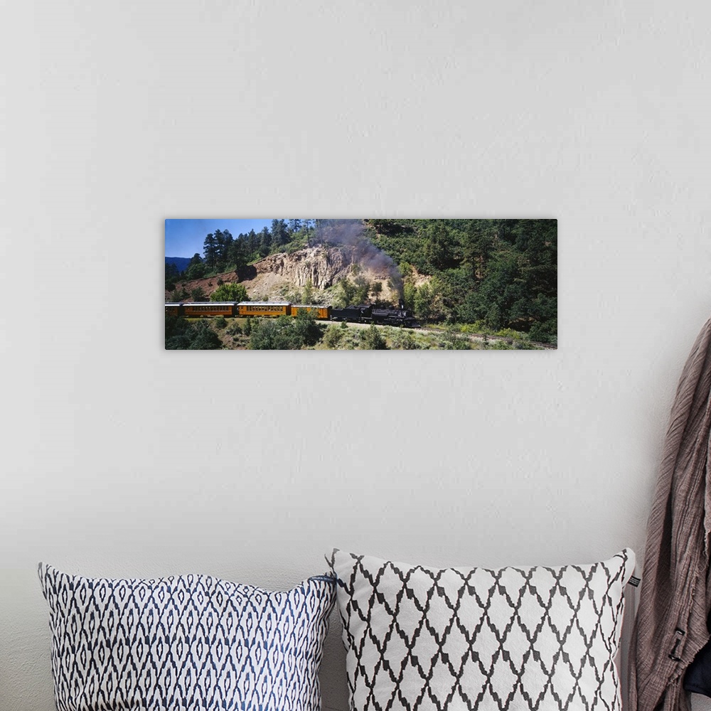 A bohemian room featuring This is a panoramic photograph of a vintage engine and train cars passing through the mountains o...