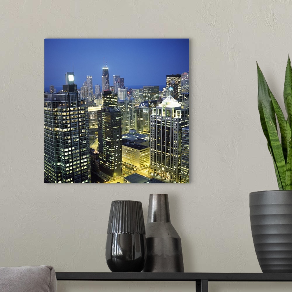 A modern room featuring Square photo print of tall buildings in downtown Chicago lit up at night.
