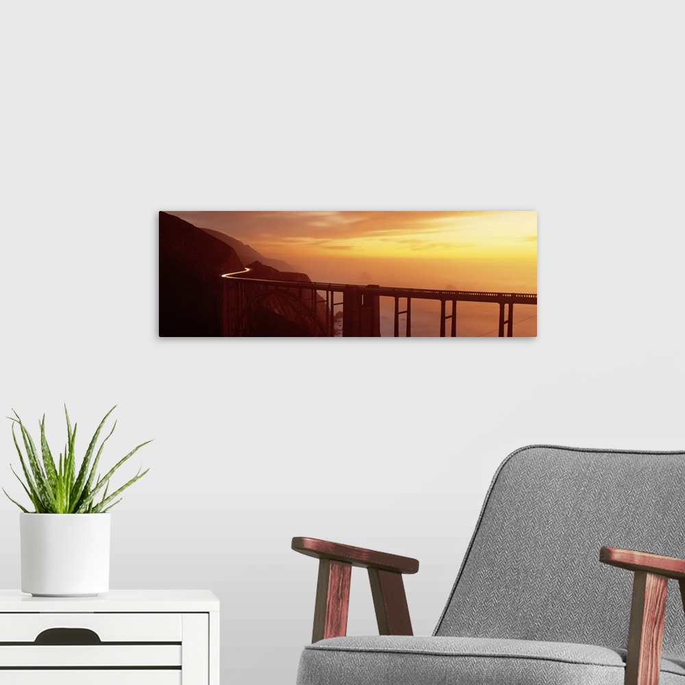 A modern room featuring Panoramic photograph of overpass winding through mountains over the ocean at sunset.