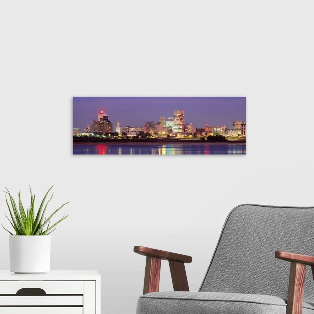 A modern room featuring Panoramic photograph of skyline with buildings lit up and reflecting off the waterfront at night.