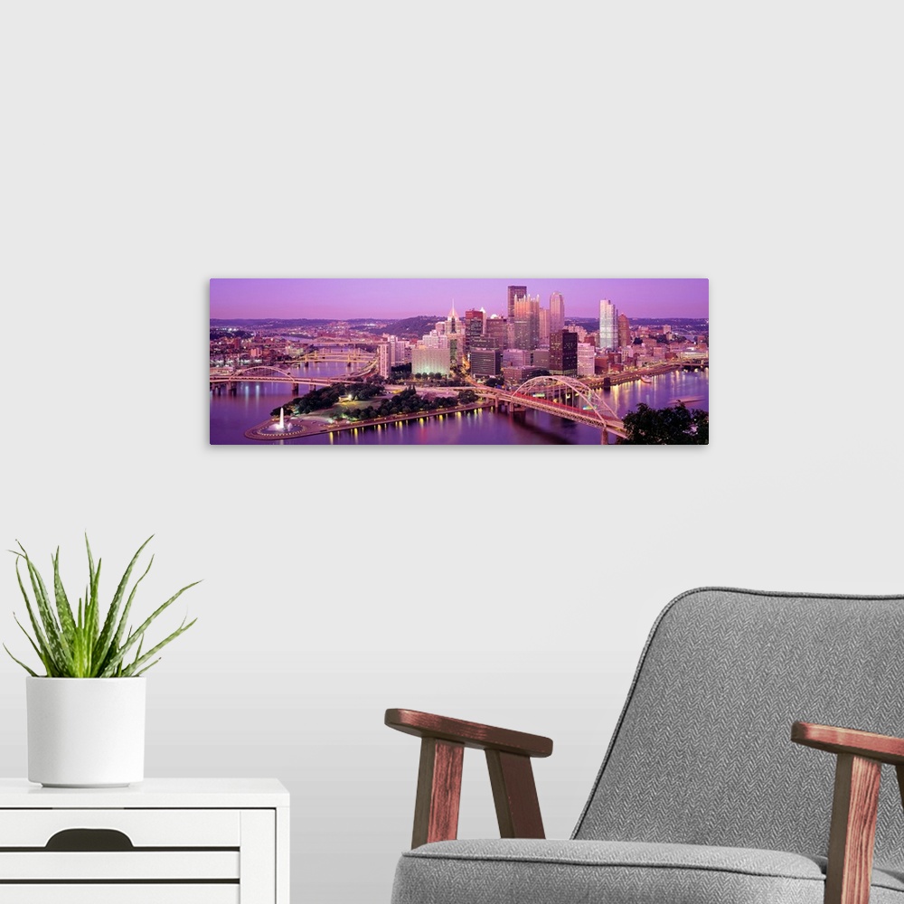 A modern room featuring Panoramic photograph of downtown Pennsylvania as the sun sets.  There are building, bridges, a fo...