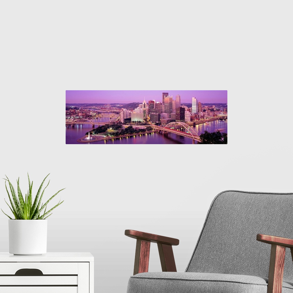 A modern room featuring Panoramic photograph of downtown Pennsylvania as the sun sets.  There are building, bridges, a fo...