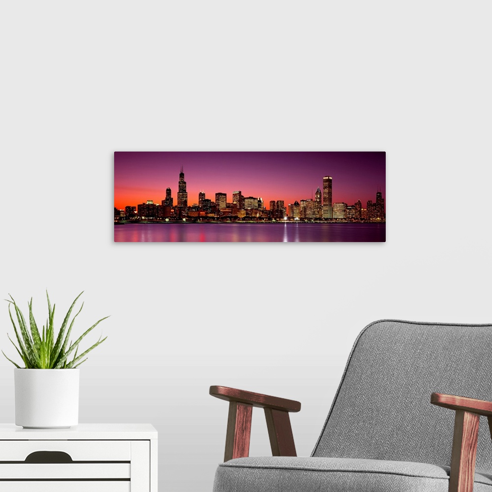 A modern room featuring Panoramic photograph of the busy skyline taken at dusk in Chicago, Illinois.  The bright lights c...