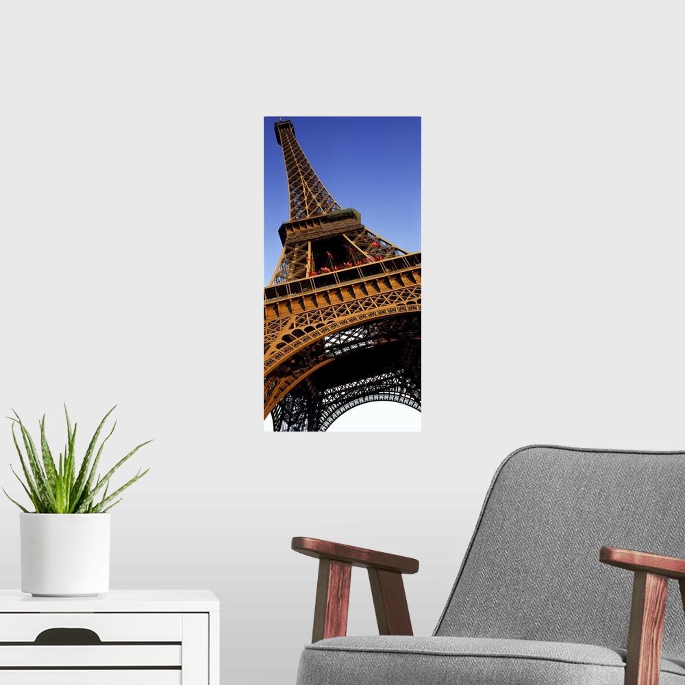 A modern room featuring Vertical, close up, low angle photograph of the Eiffel Tower against a blue sky.