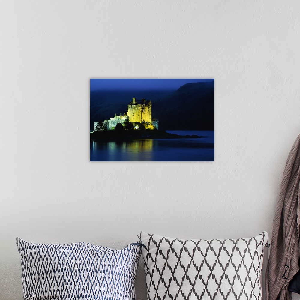 A bohemian room featuring Eilean Donan Castle illuminated at night, water reflection, Conchra, Scotland.