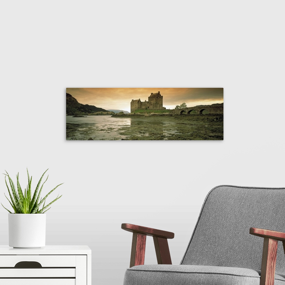 A modern room featuring Wide angle photograph taken of a castle in Scotland under a dusk sky with wet land shown in the f...